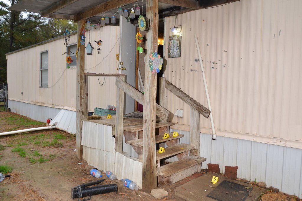 A photo shows the back entrance of a home with hanging decorations and bullet holes. Numbered yellow evidence markers are placed around the stairs leading up to the front door.