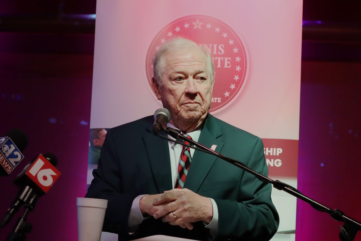 Haley Barbour, an old man with white hair, stands at a microphone