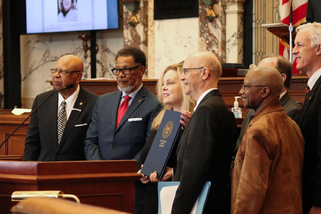 Woman holding certificate of honor from the Mississippi Senate House.