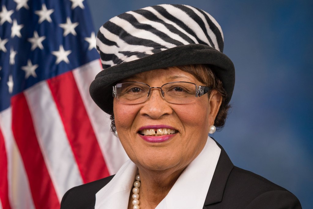 Woman smiles for a photo with the American flag behind her.