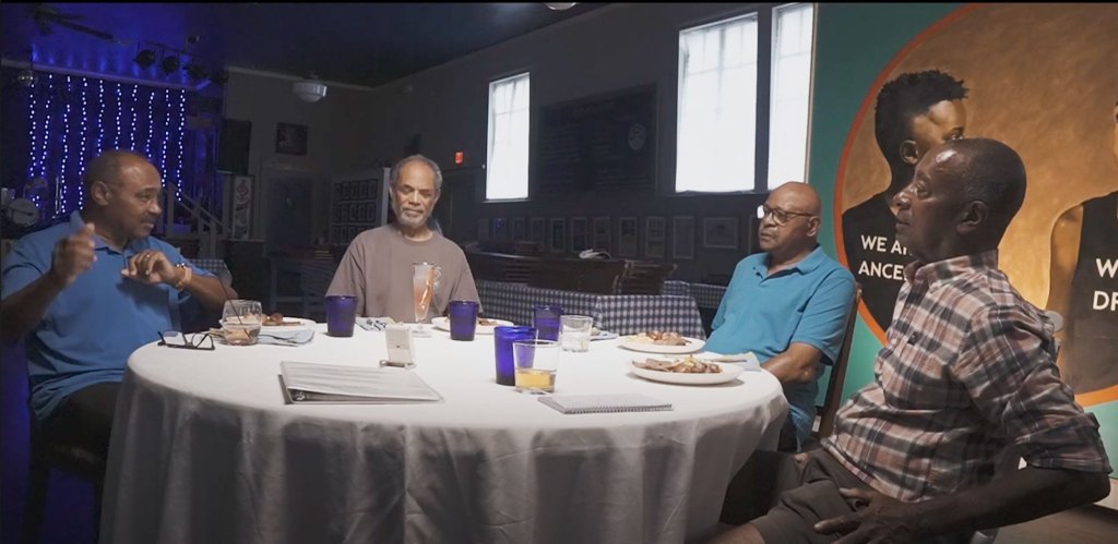 Men sitting a table having a discussion with blue cups on the table