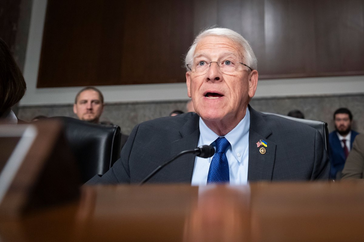 Chairman Roger Wicker speaking in a room of people wearing a gray jacket with a blue shirt and tie.