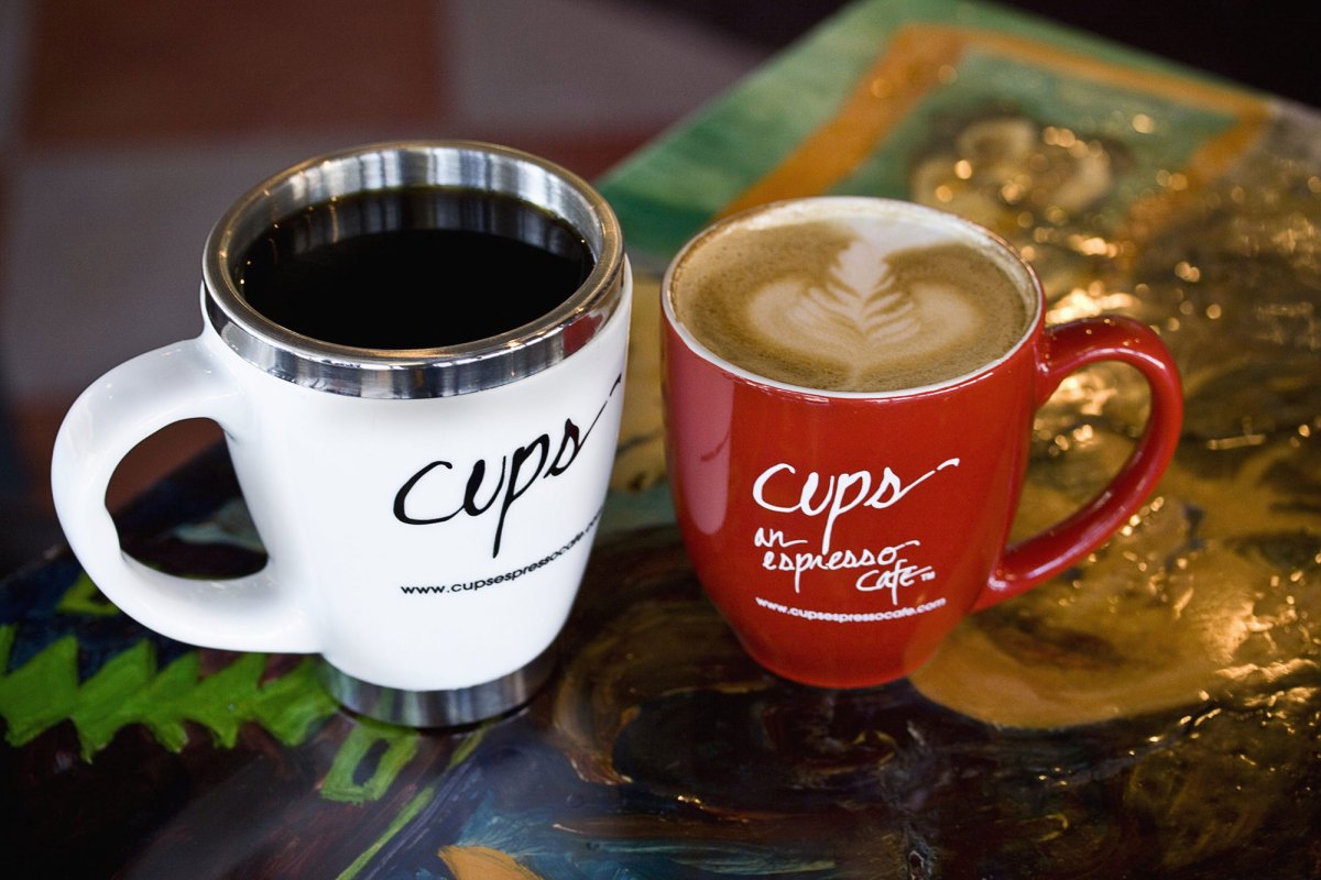 A white and red coffee cup filled with coffee sits on a table.