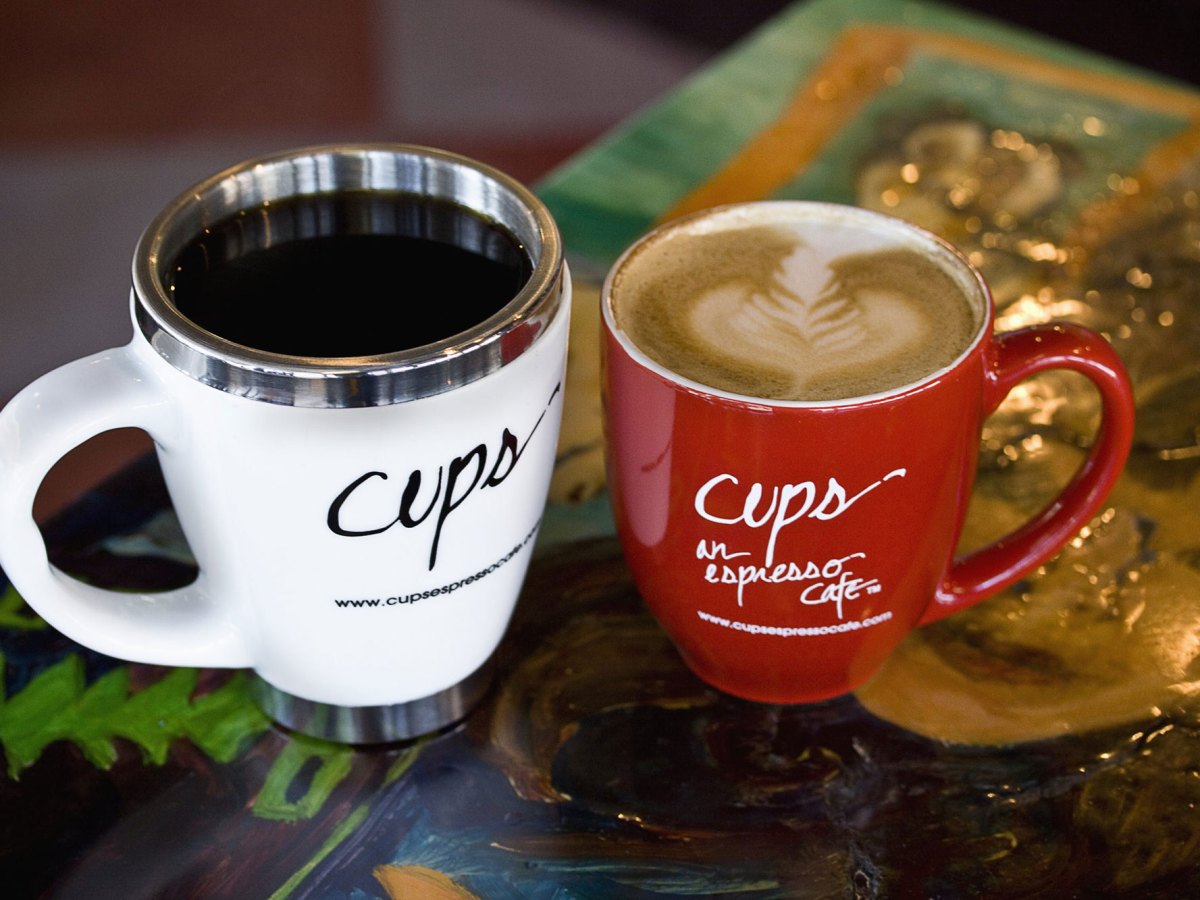 A white and red coffee cup filled with coffee sits on a table.