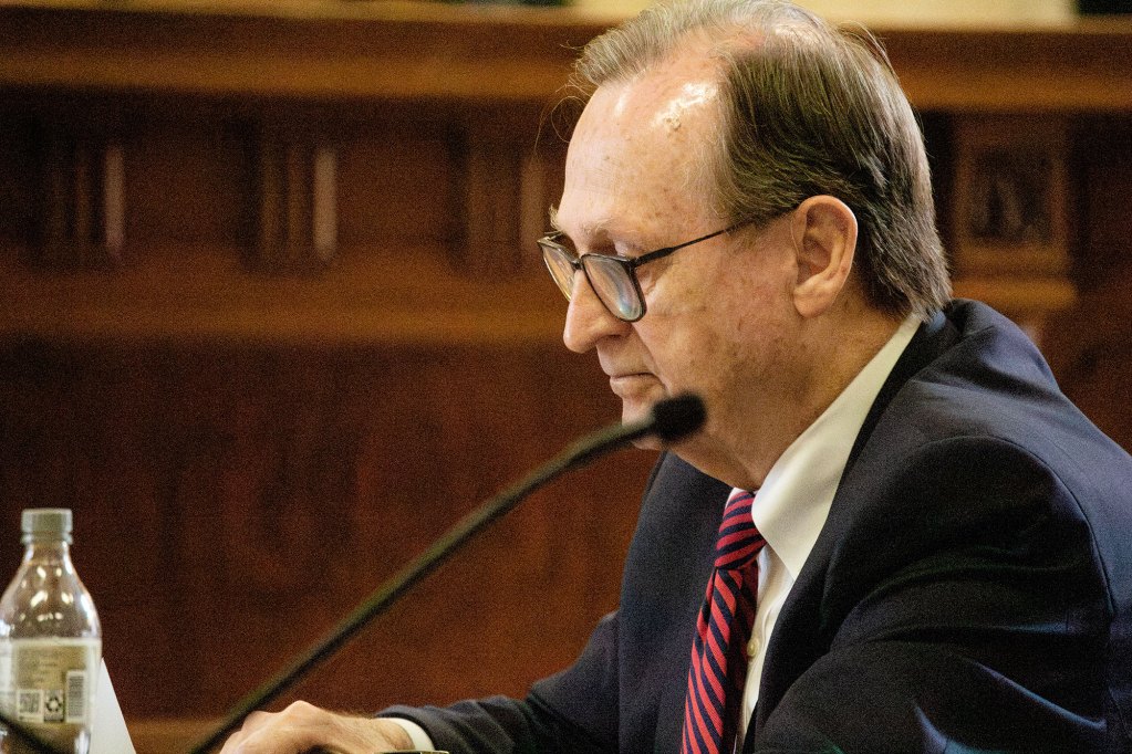 A man looks down while sitting next to a microphone