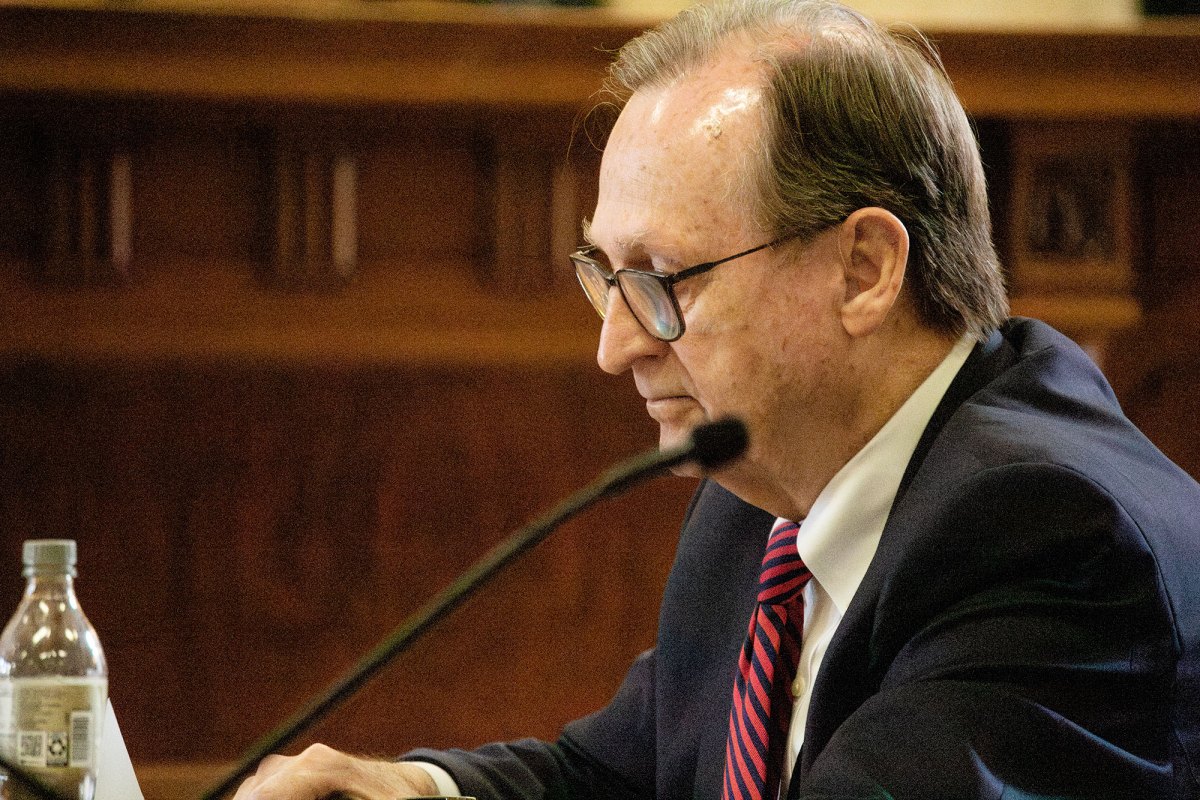 A man looks down while sitting next to a microphone