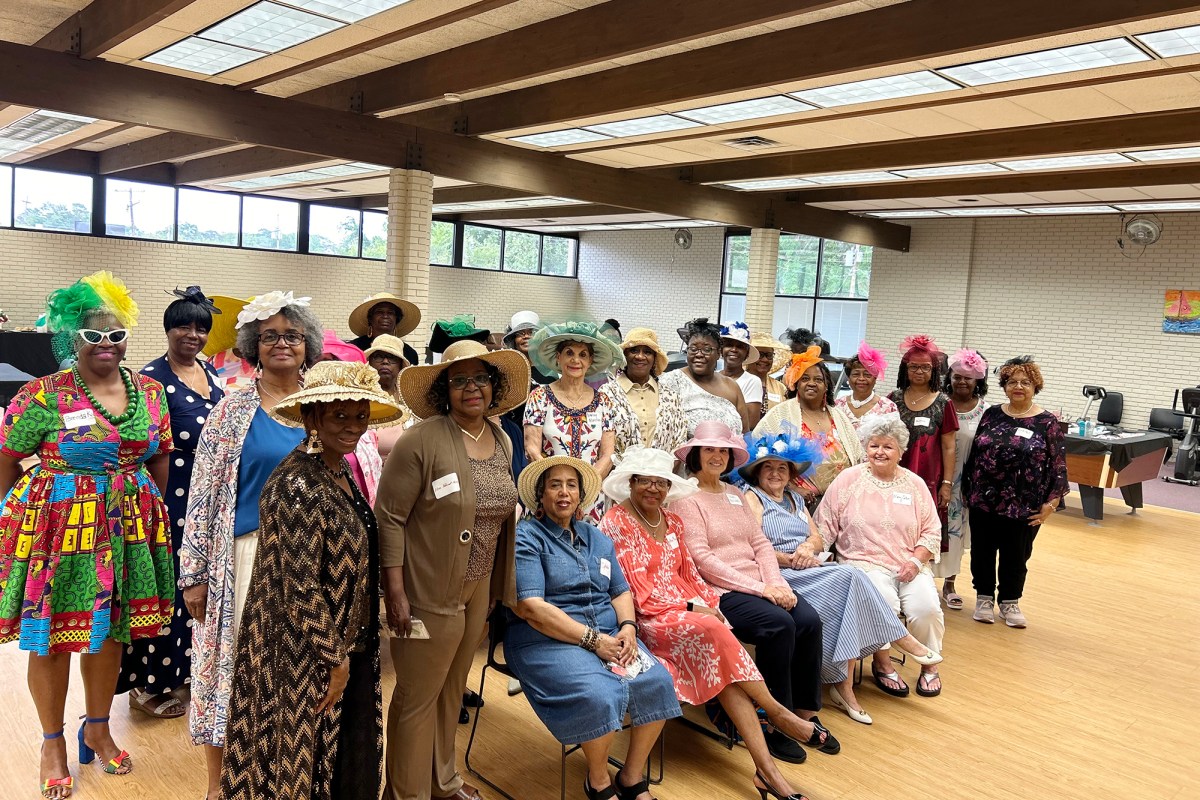 Women in hats stand together in a room for a photograph.