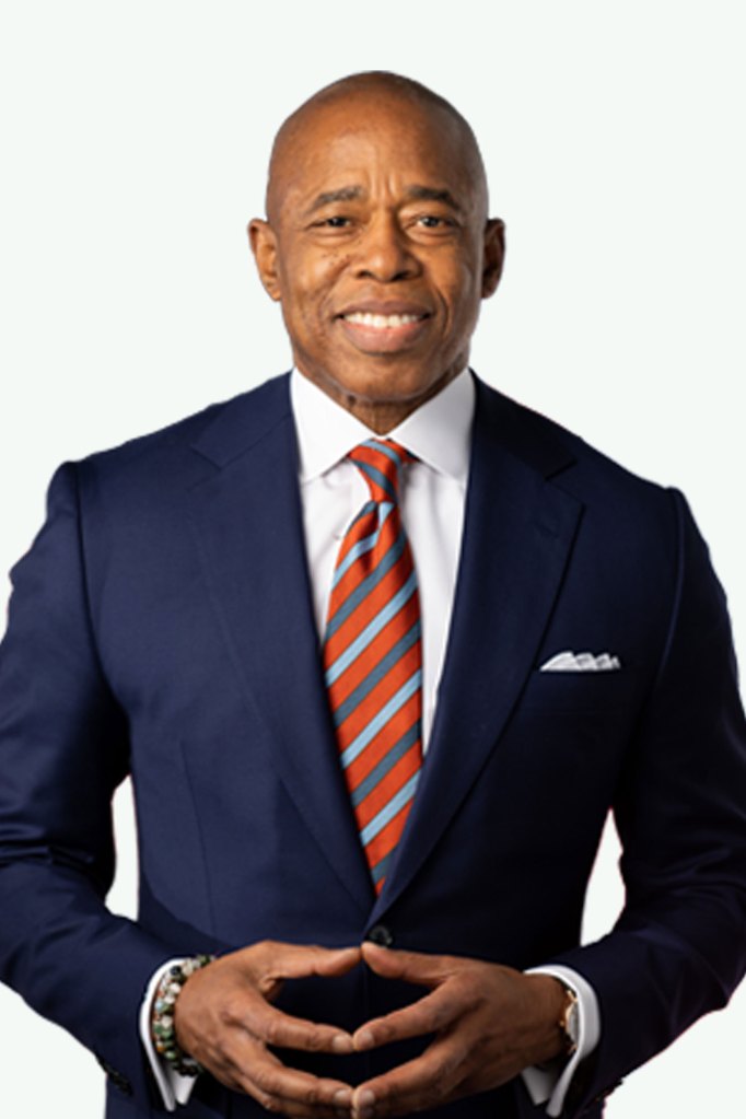 A man in a navy suit with bold orange striped tie on a neutral background
