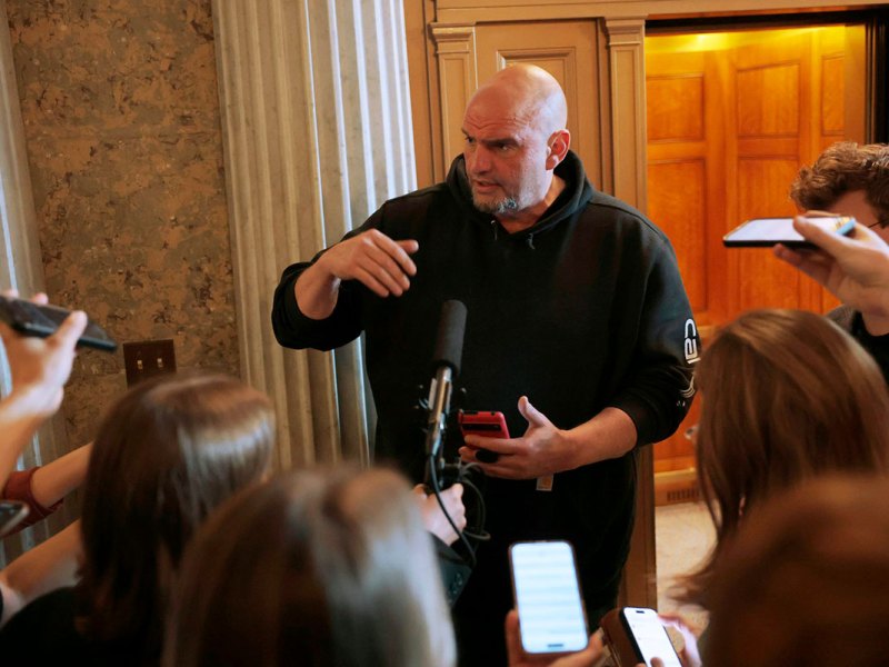 A man in a black hoodie speaks to reporters in legislative building