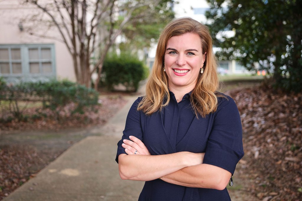 A woman smiles at camera wearing a navy blue dress.