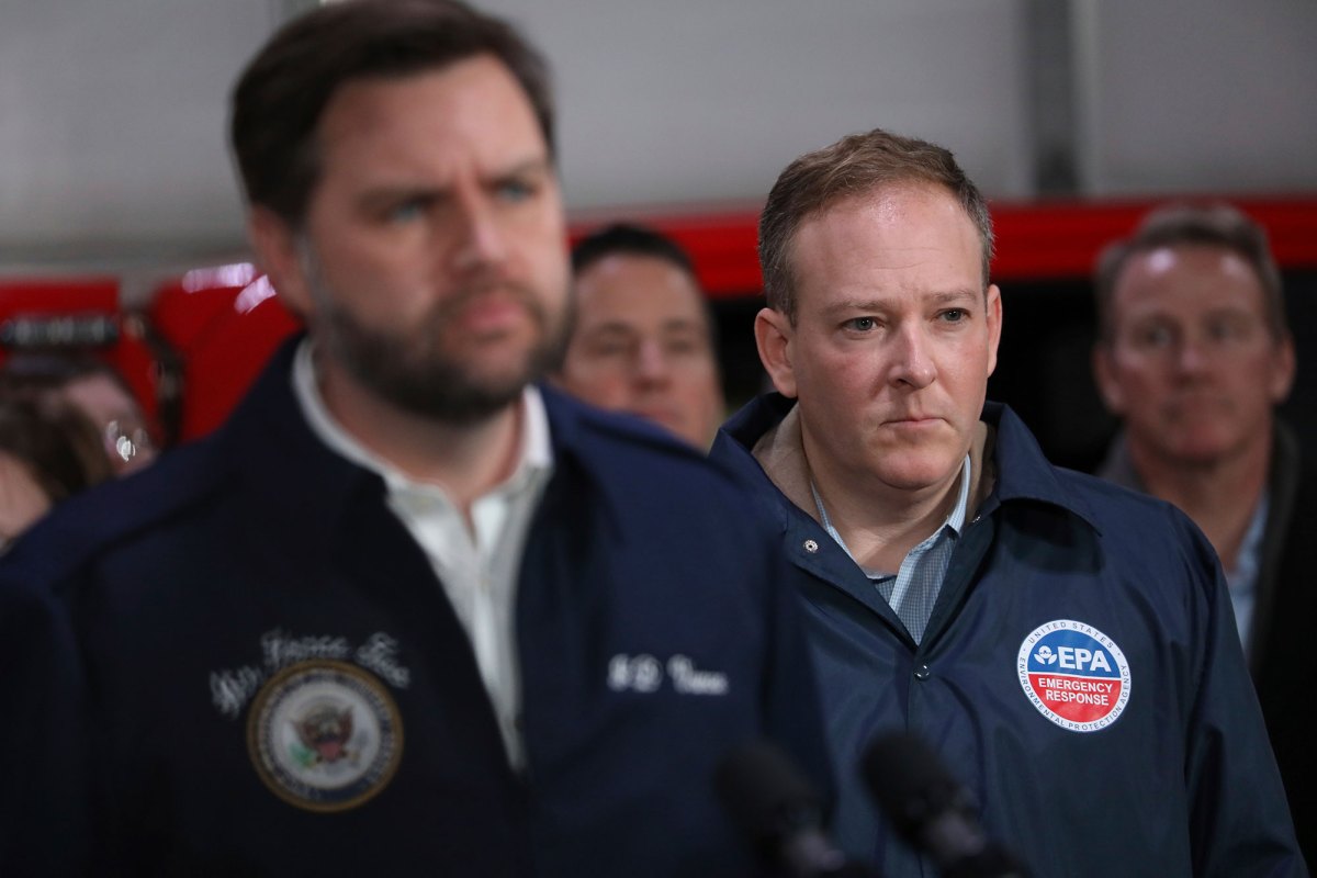 An indoor scene of me in blue jackets listening as one speaks at a press podium