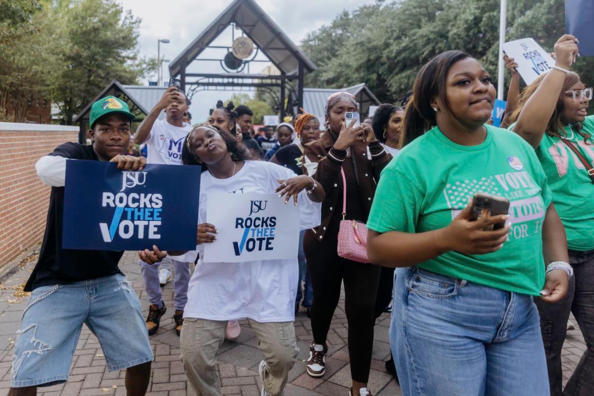 Multiple students walk while holding signs encouraging students to vote, holding posters that say “JSU Rocks Thee Vote.”