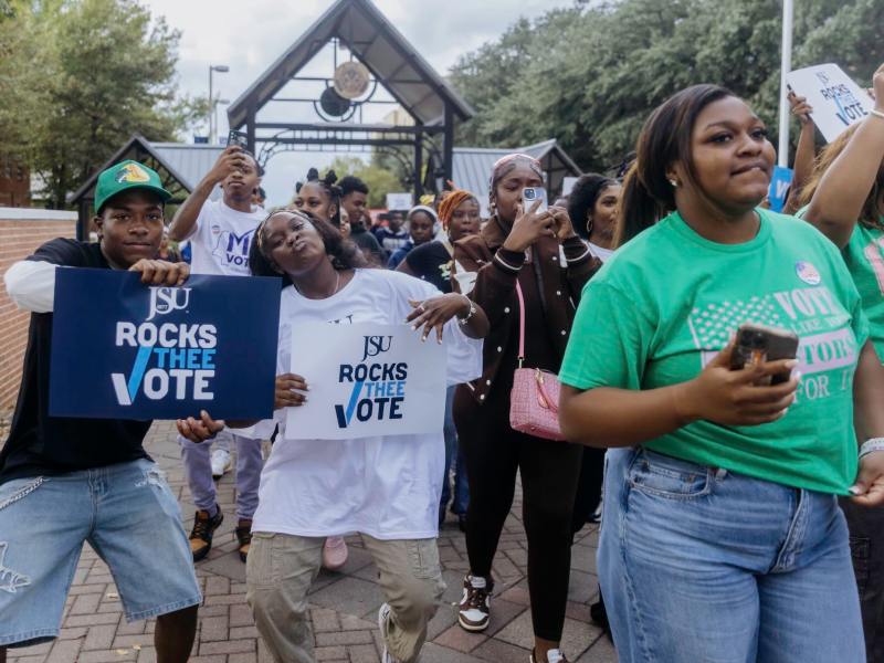 Multiple students walk while holding signs encouraging students to vote, holding posters that say “JSU Rocks Thee Vote.”