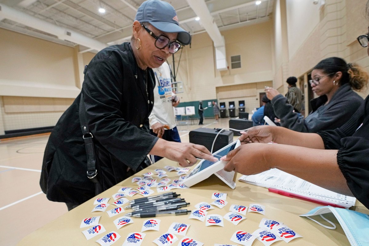 A woman is seen checking in at a polling place inside a gymnasium