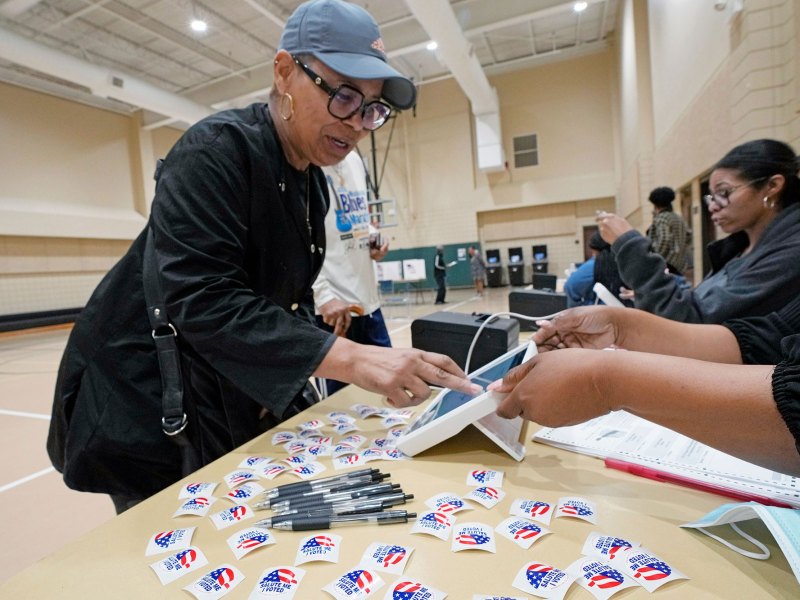 A woman is seen checking in at a polling place inside a gymnasium