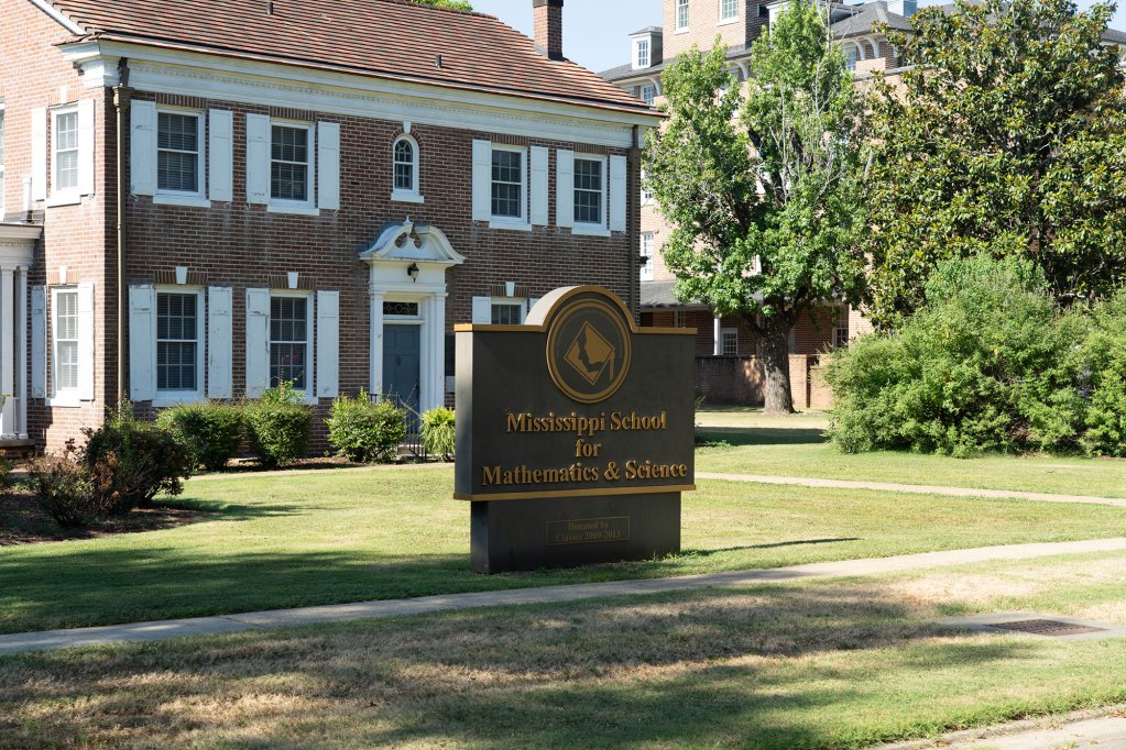 A sign outside of a two story red brick building that reads Mississippi School for Mathematics and Science