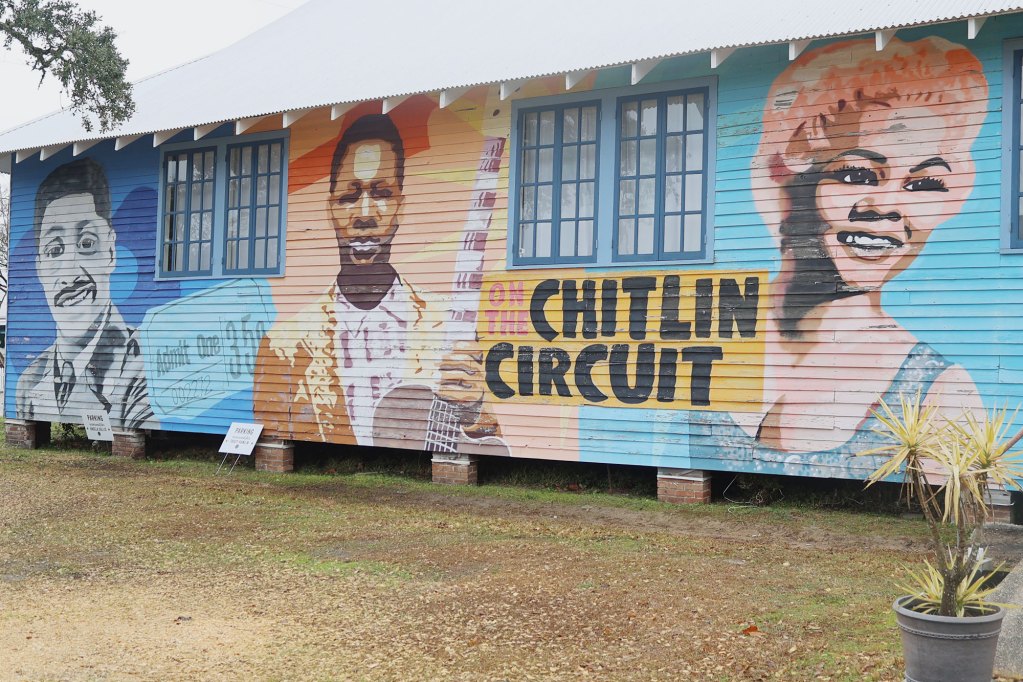 Murals of people adorn the outer walls of a building.