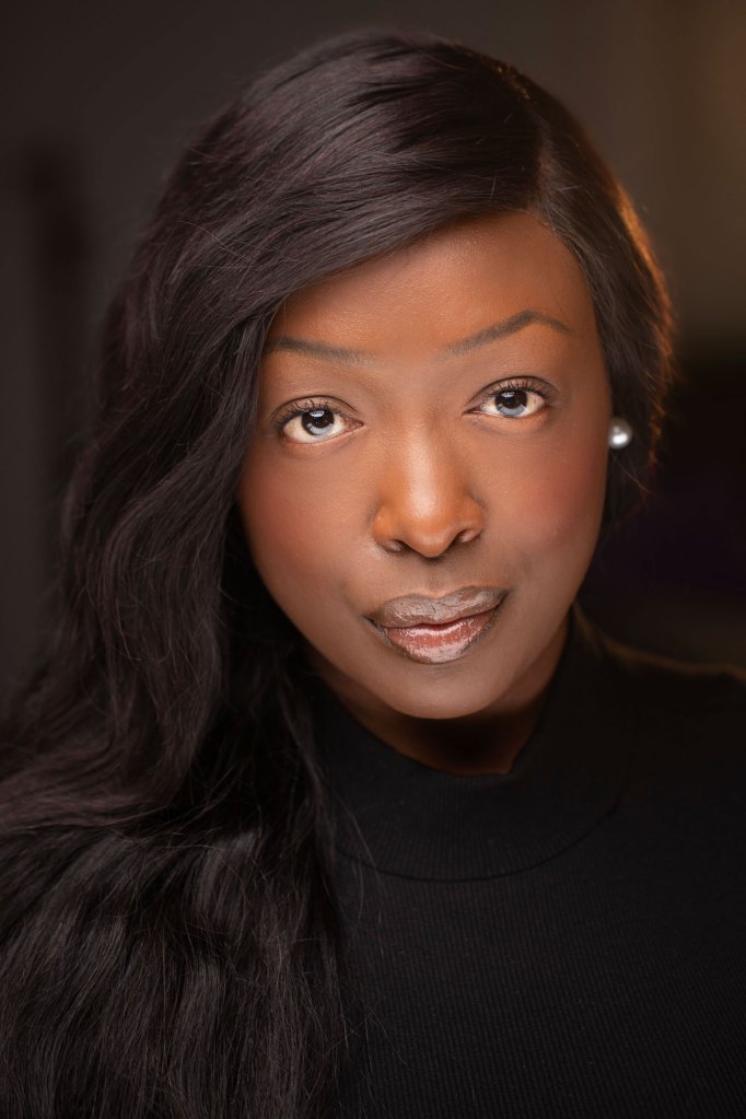 A woman in black looks at the camera for a headshot photo.