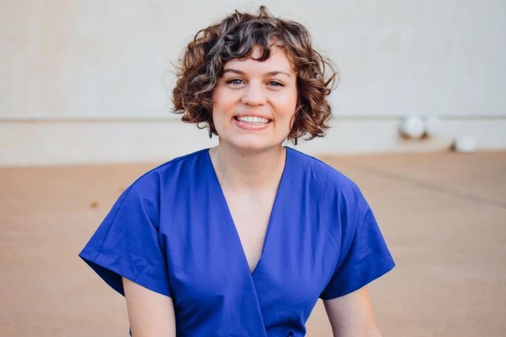 A woman in blue looks at the camera for a headshot photo.