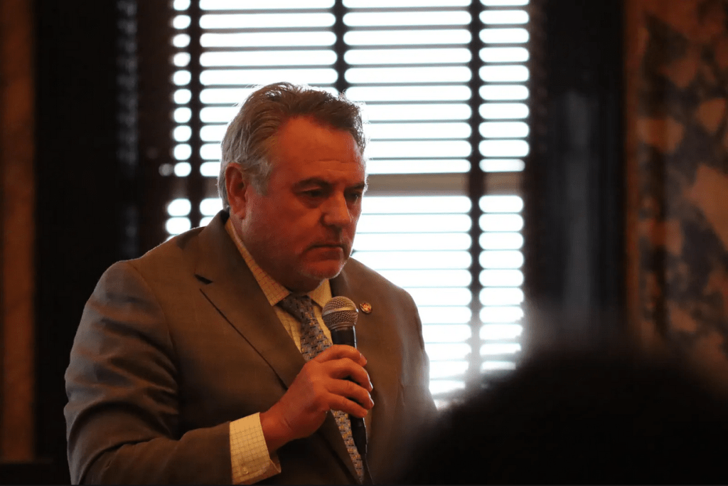 A man looks down while holding a microphone.