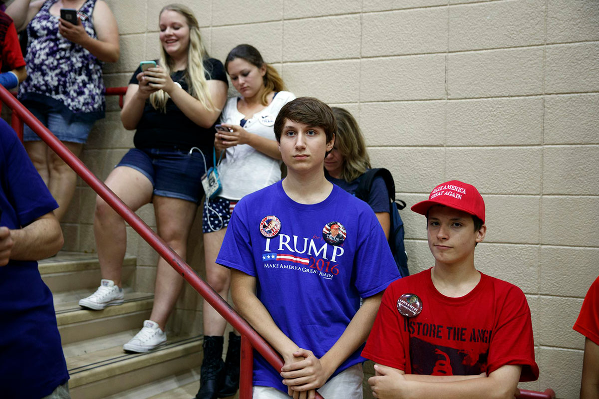 A row of teens standing on a stairwell, some wearing Trump clothing
