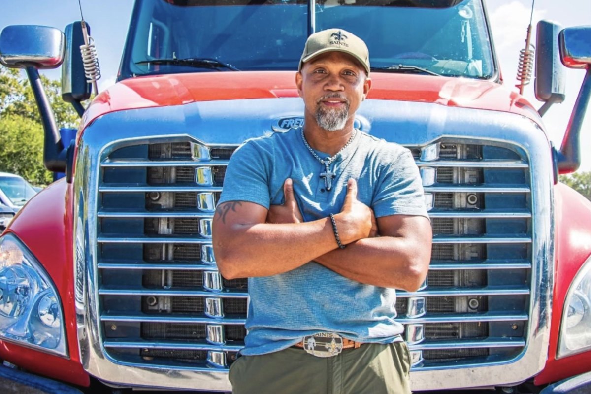 A man stands in front of a red 18 wheeler truck.