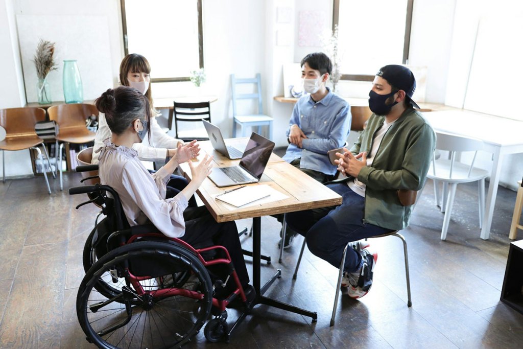 Woman on wheelchair with her colleagues at office