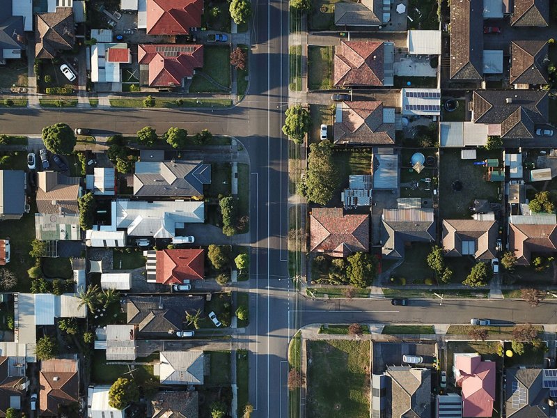 A top down view of a neighborhood of houses with long shadows near sunset
