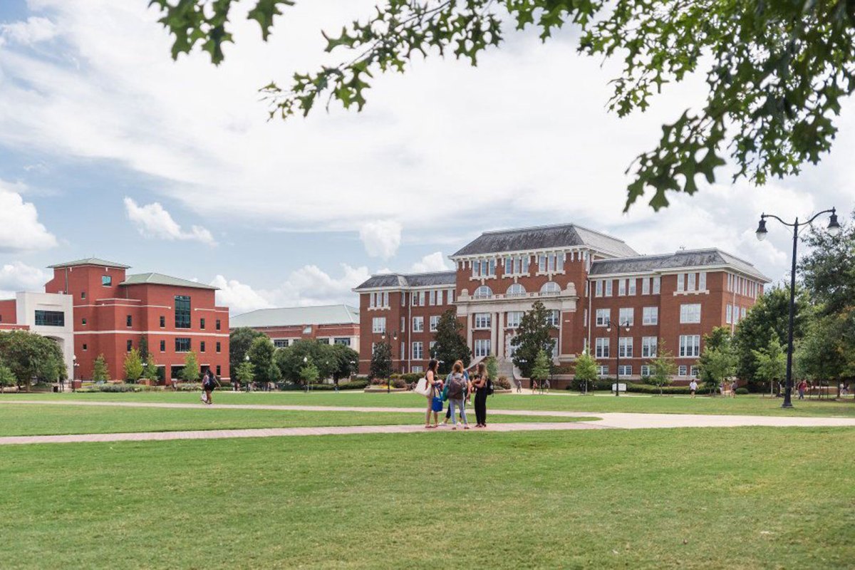 a photo of an academic building with students standing on a campus crosswalk in front of it