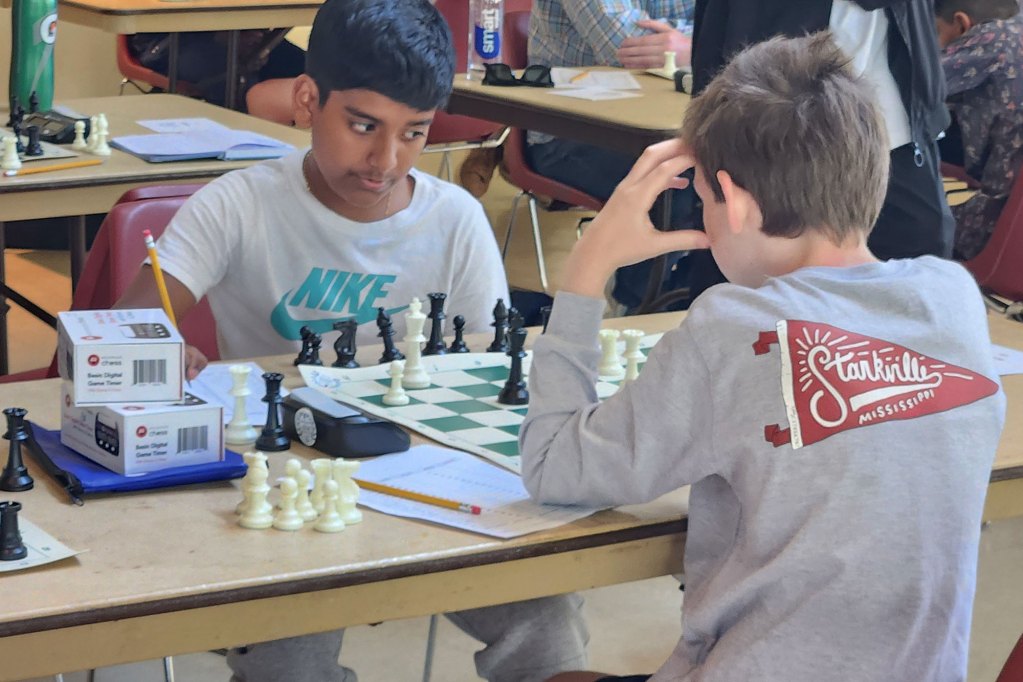 Two young boys play chess together