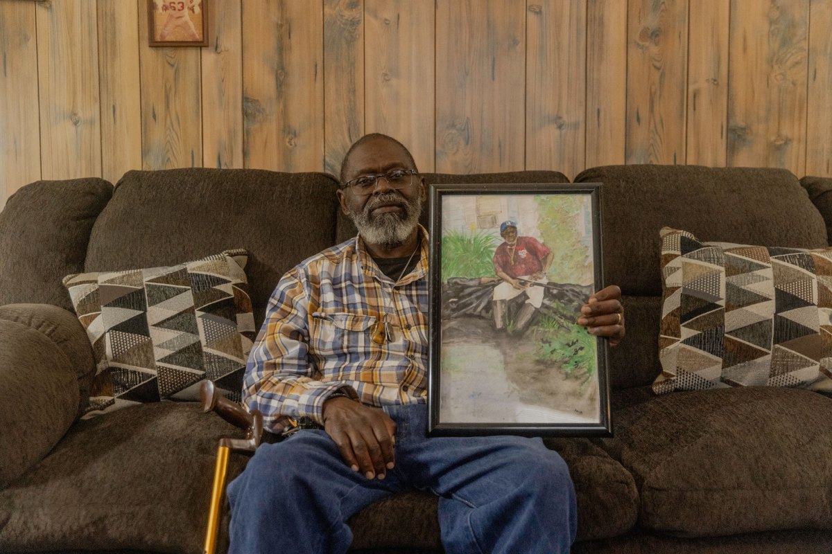A man sitting on a brown couch holding a photo of himself