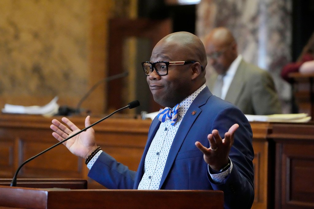A black lawmaker in a blue suit and bowtie, speaking on the senate floor