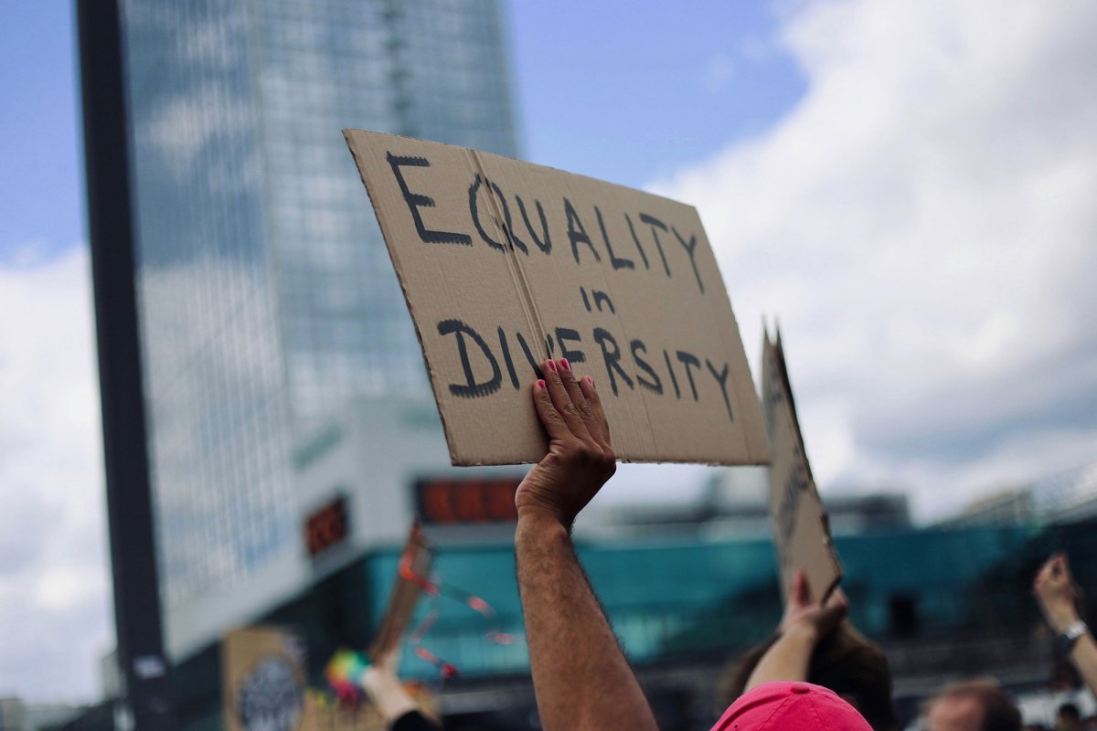 Hands holding sign with "Equality in Diversity" written on it.