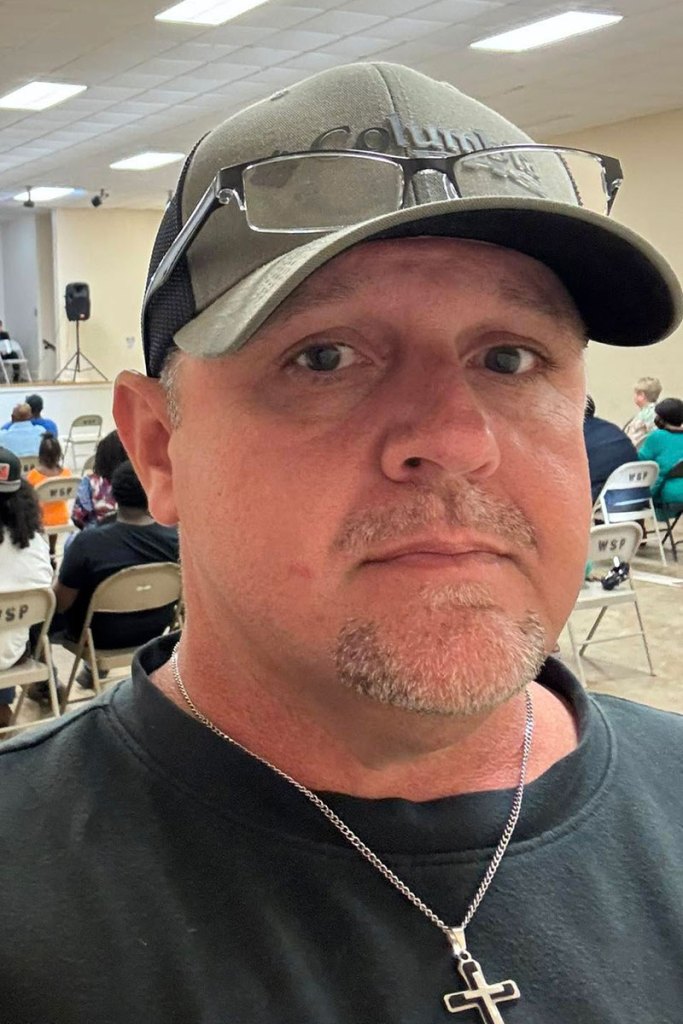 A selfie of a man wearing a cross and baseball cap