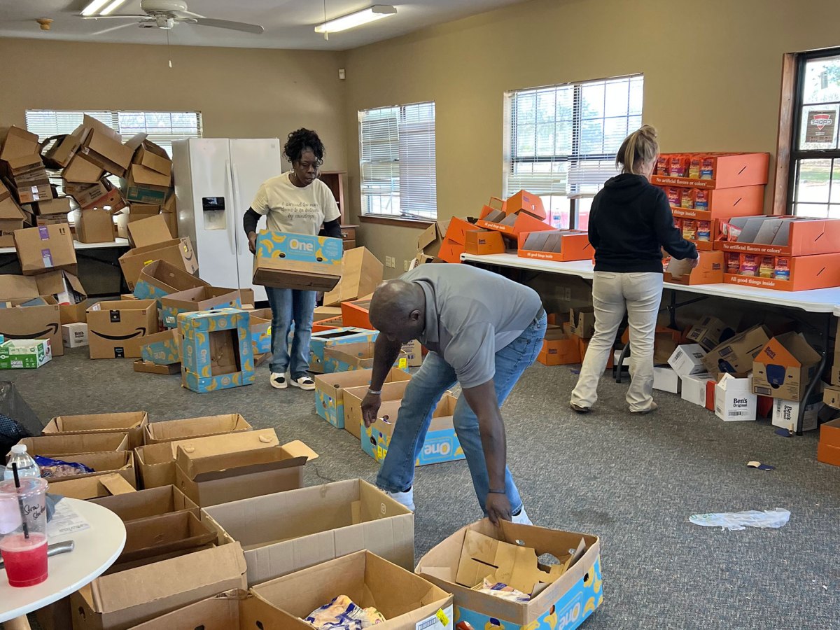 Three people work in a room organizing cardboard boxes