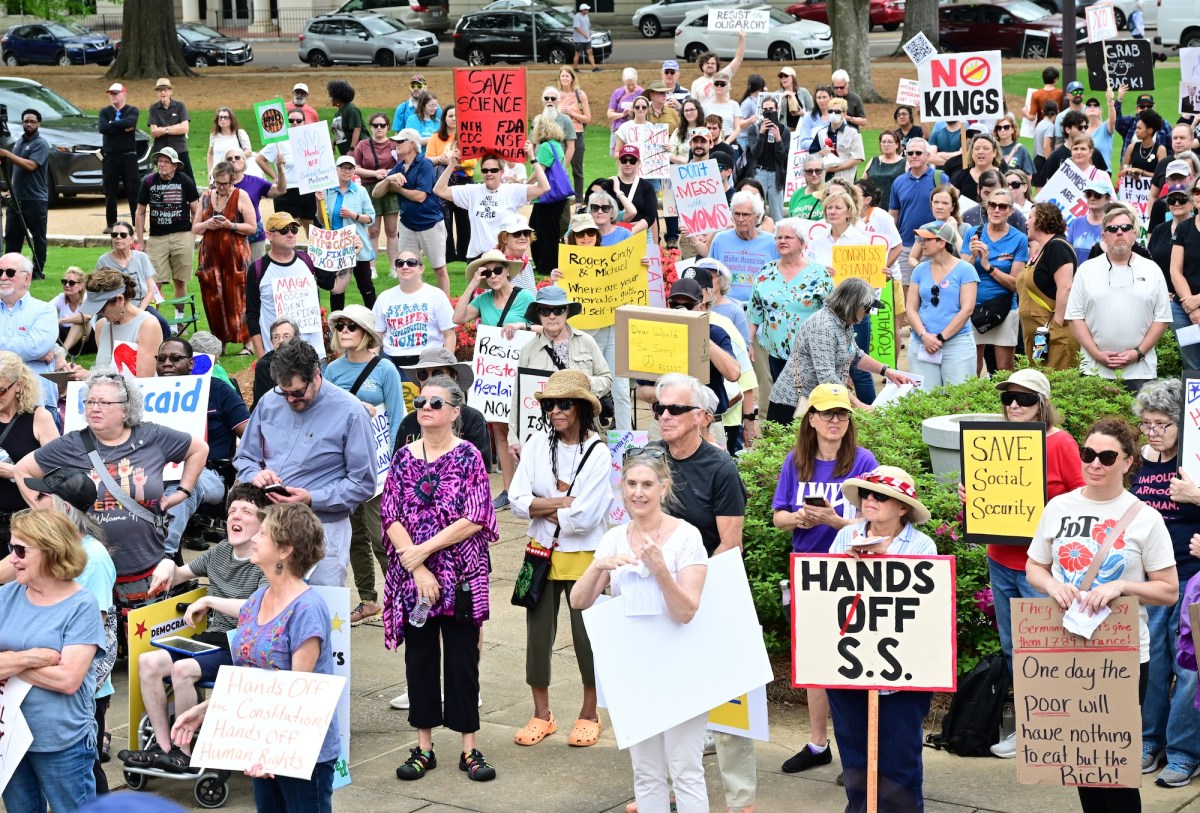 a photo shows a crowd of protesters holding signs gathered together. Signs say things like, "Save Science - NIH, CDC, FDA, NSF, NOAA, EPA" and "No Kings" and "Hands Off S.S." and "Save Social Security" and "Don't Mess With Moms" and "They want 1939 Germany Let's Give them 1789 France - One Day the Poor Will Have Nothing to Eat But the Rich" and "Hands off the Constitution Hands off Human Rights" and "Roger, Cindy & Michael - Where are your morals, guts and self worth?" and "MAGA - Moscow Agent, Grifting America"