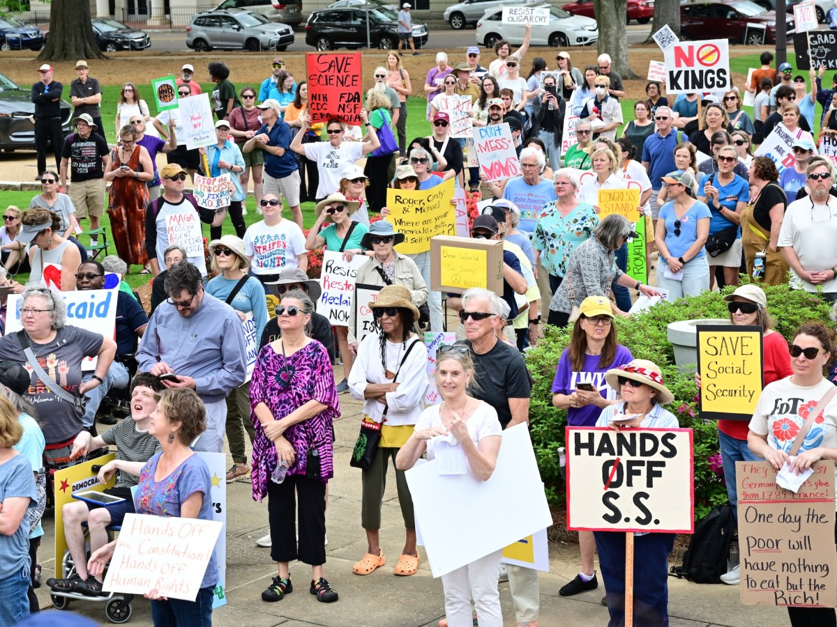 a photo shows a crowd of protesters holding signs gathered together. Signs say things like, "Save Science - NIH, CDC, FDA, NSF, NOAA, EPA" and "No Kings" and "Hands Off S.S." and "Save Social Security" and "Don't Mess With Moms" and "They want 1939 Germany Let's Give them 1789 France - One Day the Poor Will Have Nothing to Eat But the Rich" and "Hands off the Constitution Hands off Human Rights" and "Roger, Cindy & Michael - Where are your morals, guts and self worth?" and "MAGA - Moscow Agent, Grifting America"