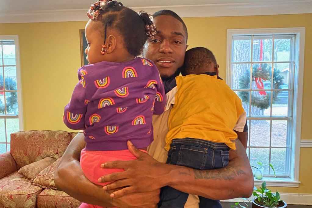 Man holding children standing in front of a yellow wall
