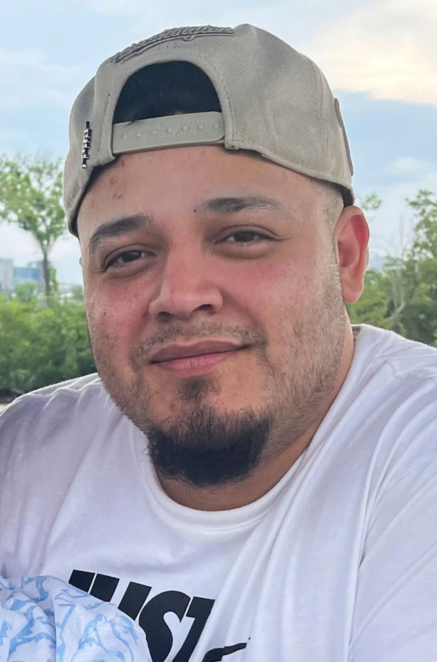 A man wearing a backwards baseball cap, smiling
