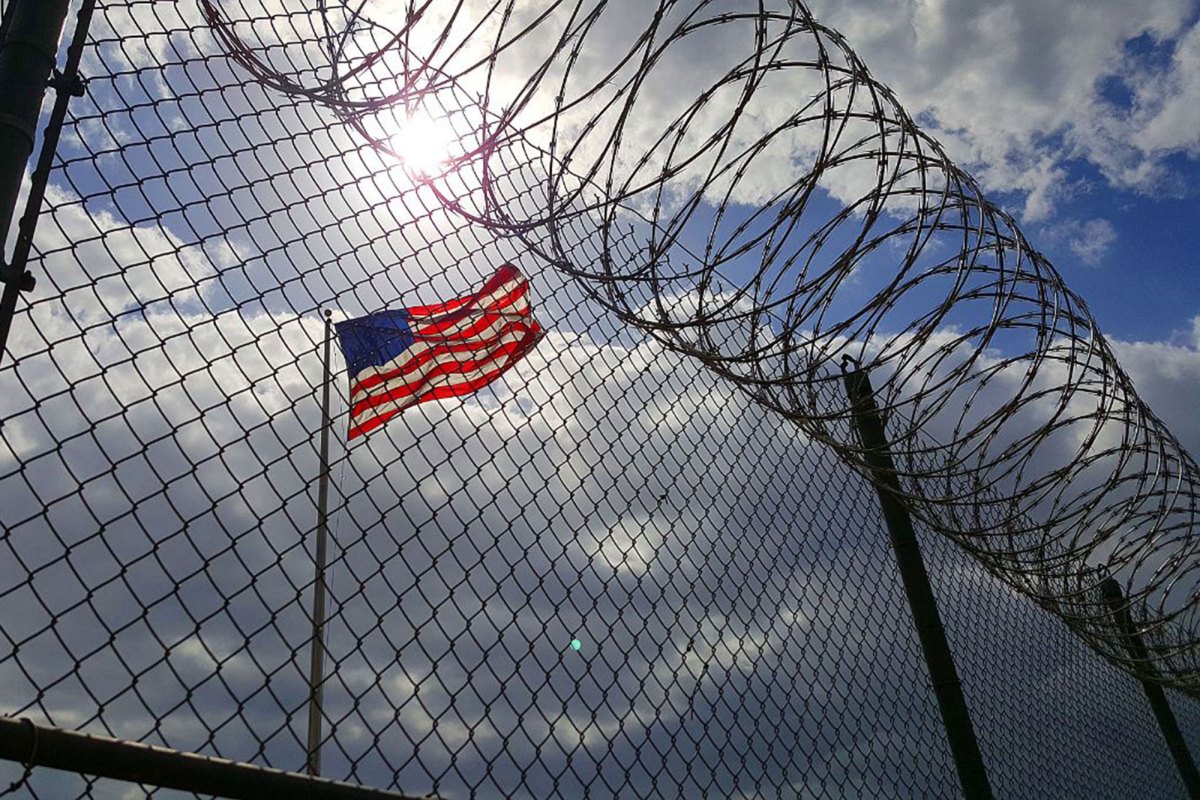 A fence with barbwire sits in front of the American flag