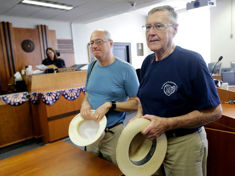 Two men inside holding their hats in their hands