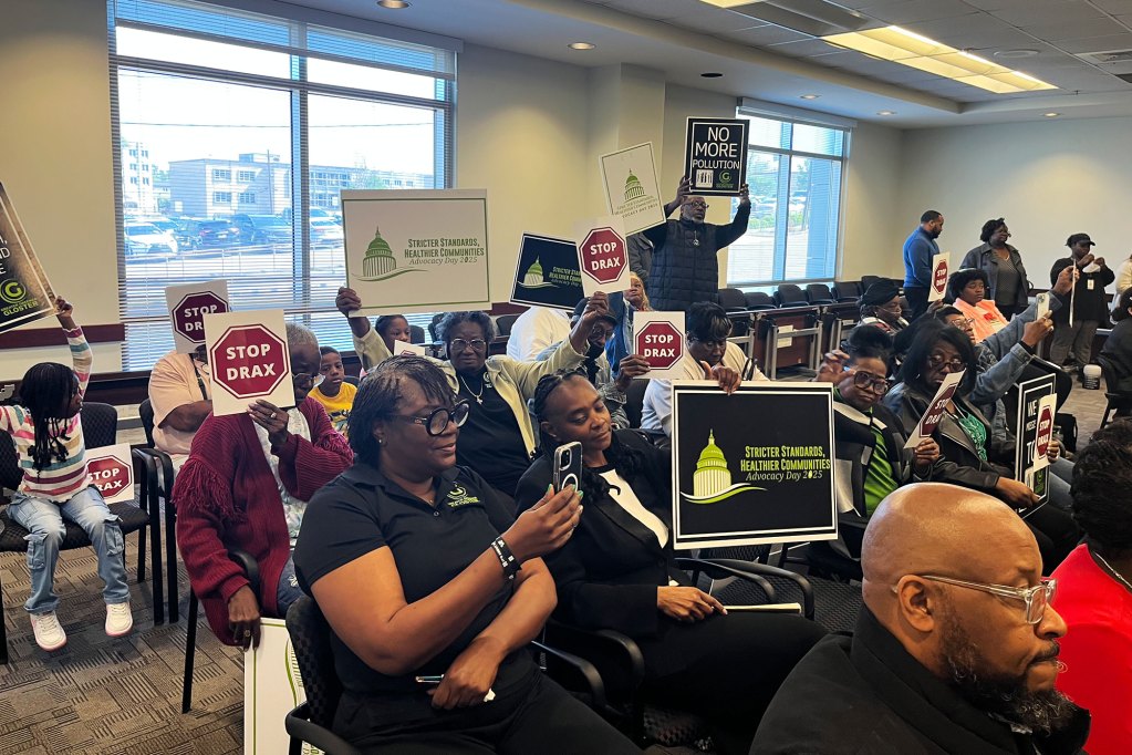A room full of people holding signs that says, "Stop Drax".