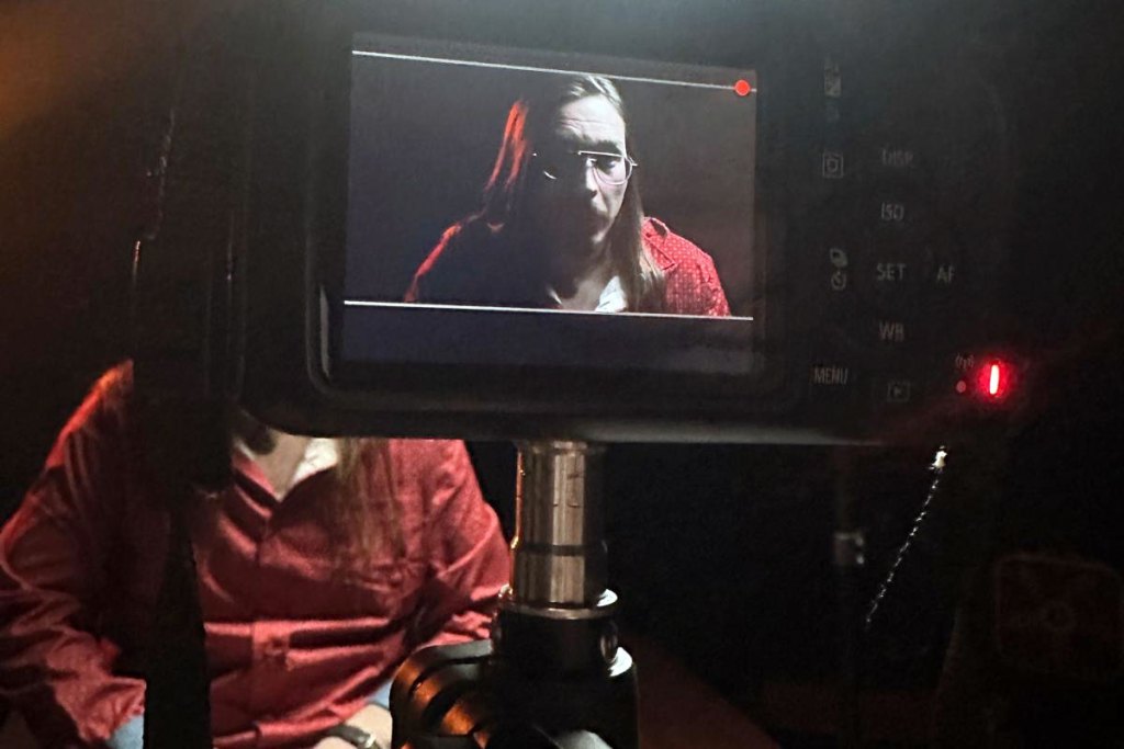 A view of a person wearing a red top as seen through a camera