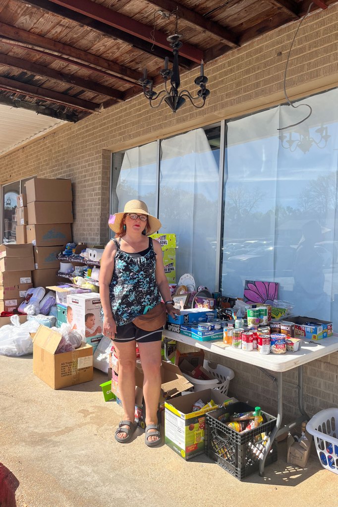 a photo of a woman standing next to a table with soup cans and other donated items