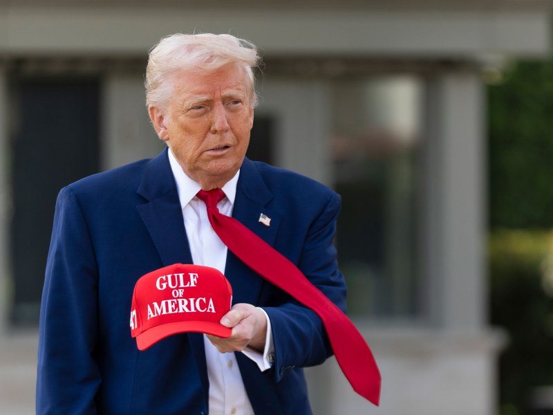President Trump wearing a blue jacket and holding a red cap titled, "Gulf of America".