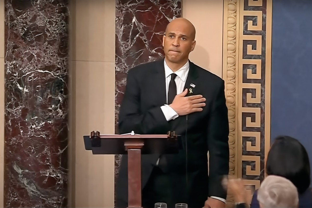 a photo of Cory Booker standing on the us senate floor and holding his chest