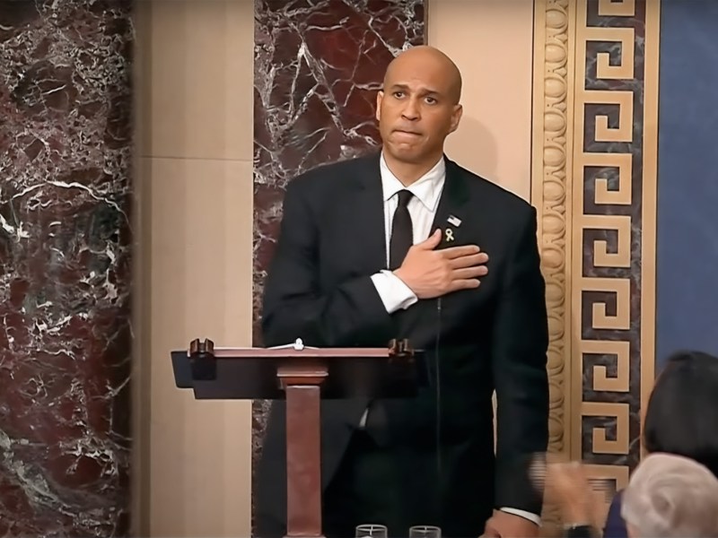 a photo of Cory Booker standing on the us senate floor and holding his chest
