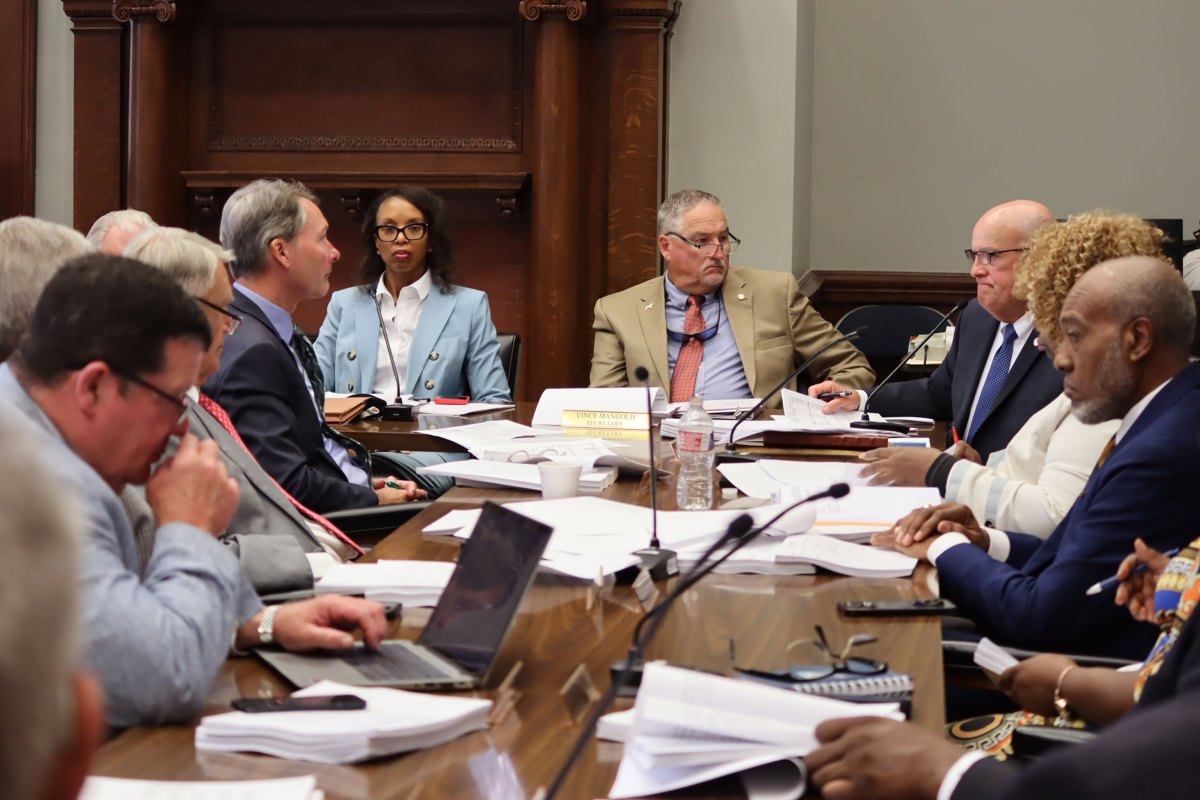 A committee of people sit around a senate meeting table