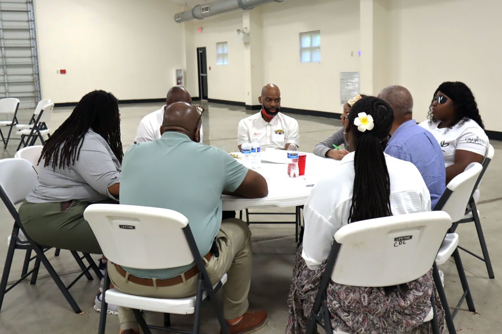 Eight people talk around a circular table