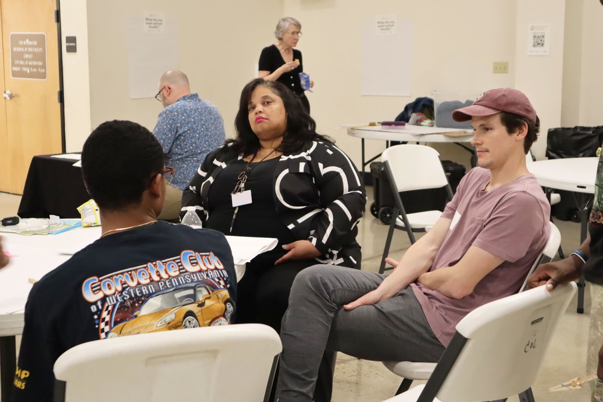 Three people sit around a circular table and talk